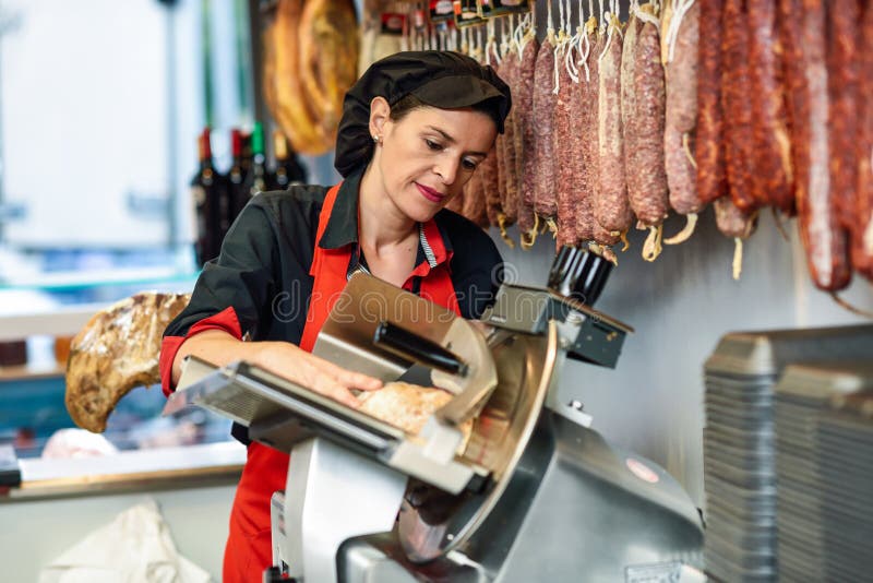 Carnicero de sexo femenino que corta el jamón de York en una cortadora fotos de archivo libres de regalías Carnicero de sexo femenino que corta el jamón de York en una cortadora fotos de archivo libres de regalías