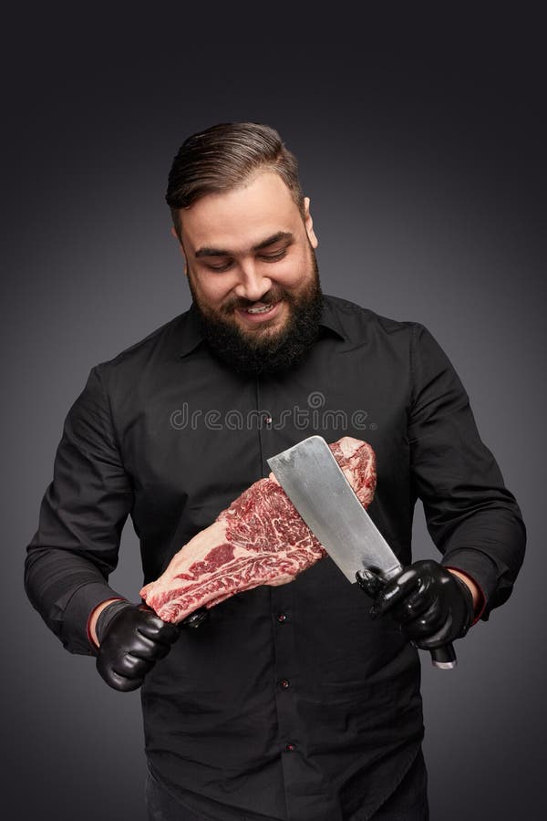 Carnicero sonriente que rasguña la carne con el cuchillo foto de archivo libre de regalías Carnicero sonriente que rasguña la carne con el cuchillo foto de archivo libre de regalías