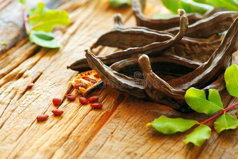 carob Здоровые органические сладостные стручки carob с семенами и листьями на деревянном столе еда здоровая стоковое фото carob Здоровые органические сладостные стручки carob с семенами и листьями на деревянном столе еда здоровая стоковое фото