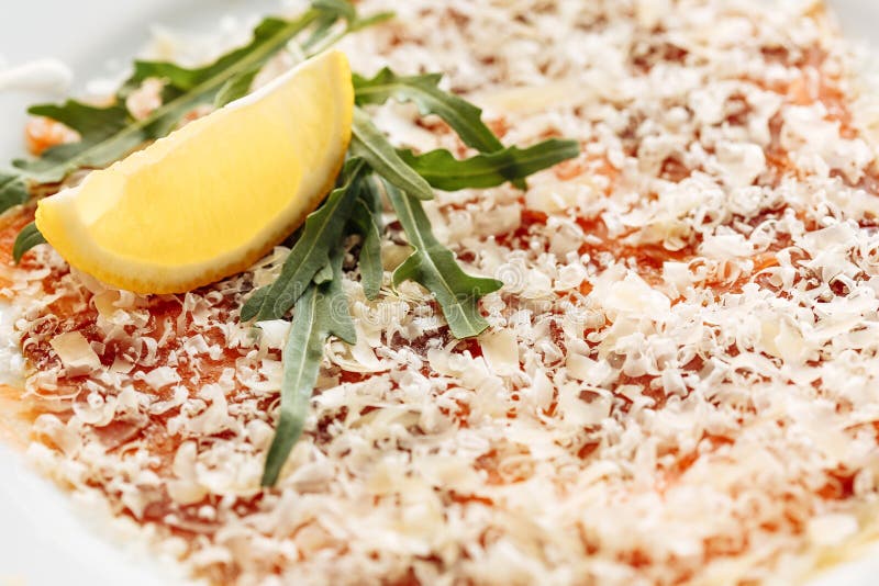 Carpaccio von den Lachsen bedeckt mit Parmesankäse, Arugula- und Zitronenscheibe Nahe Makroansicht stockfoto Carpaccio von den Lachsen bedeckt mit Parmesankäse, Arugula- und Zitronenscheibe Nahe Makroansicht stockfoto