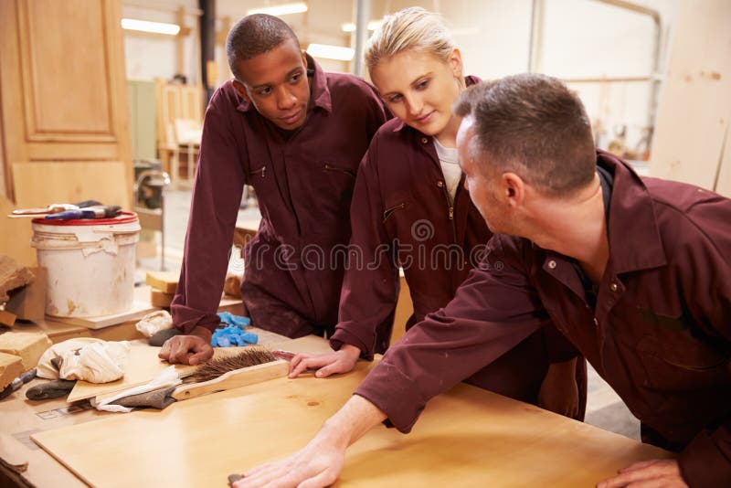 Carpenter with Apprentices Finishing Wood in Stock Image