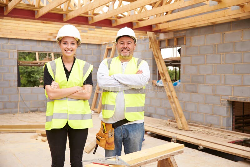 Carpenter With Female Apprentice Working On Building Site ...