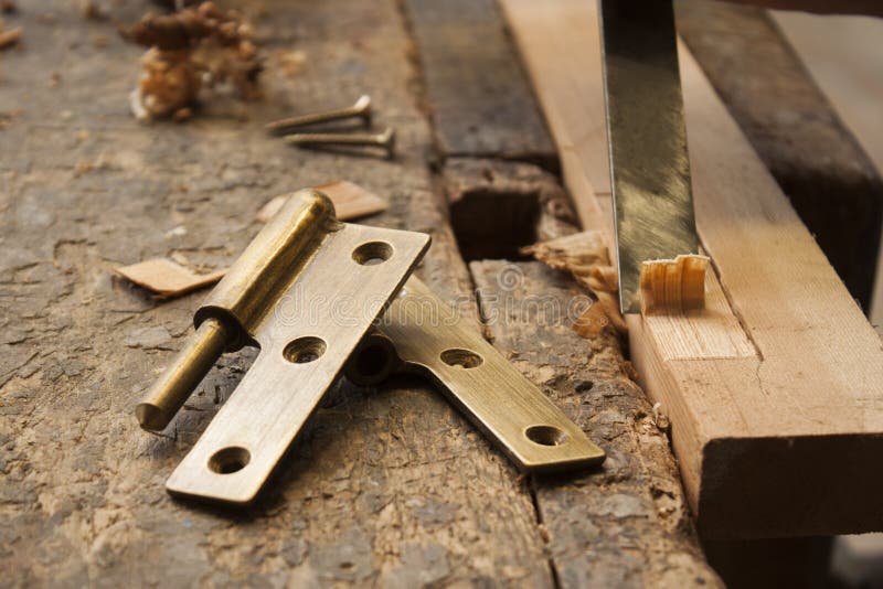 Close up of a carpenter with a hinge on a wooden plank