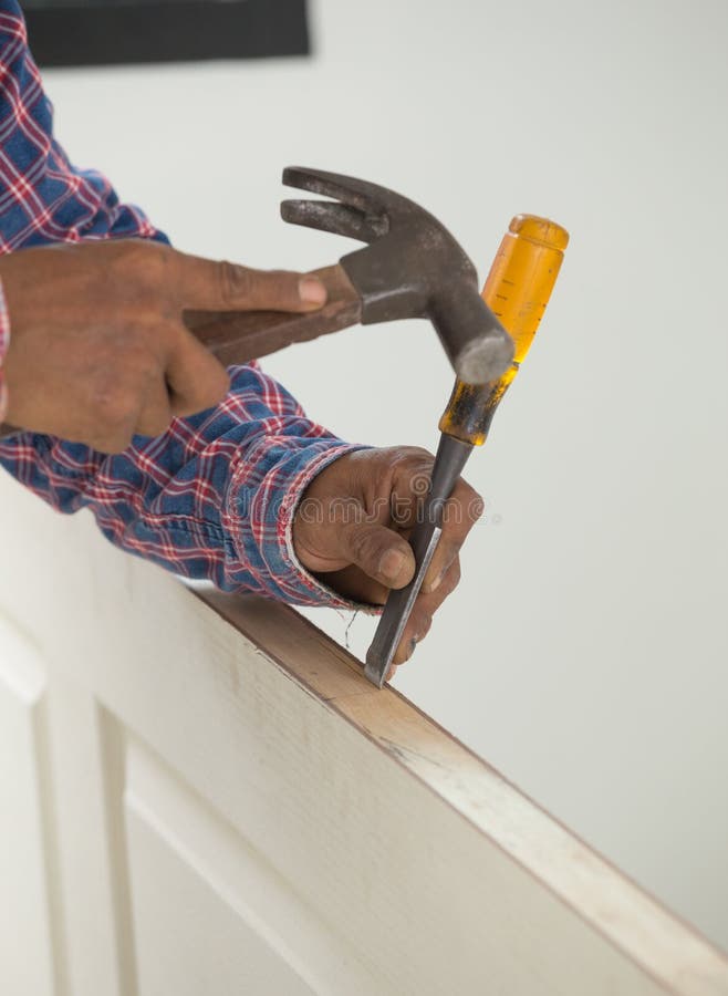 Carpenter Installer with Hammer and Chisel at Wood Door Stock Photo