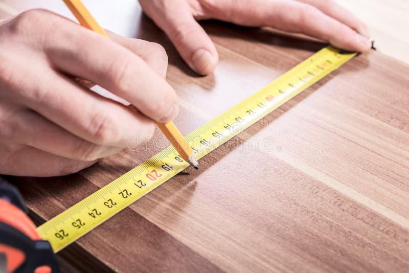 Carpenter Making a Mark with a Pencil after Measuring a Wooden Board