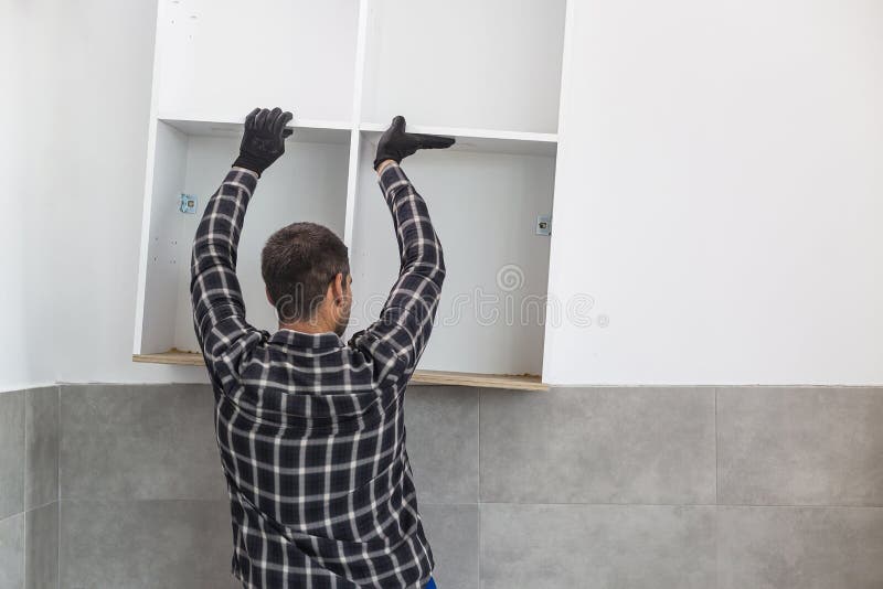 The Carpenter Places the Newly Assembled Kitchen Shelves in the