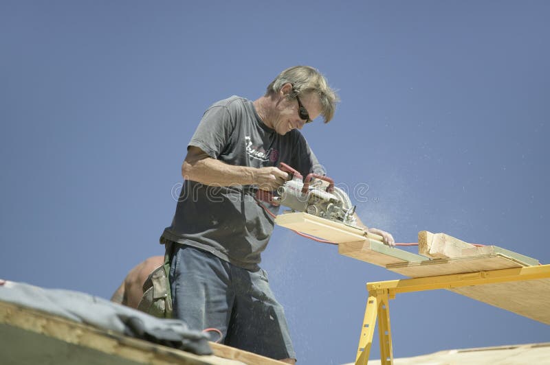 Carpenter sawing board on roof stock photos Carpenter sawing board on roof stock photos