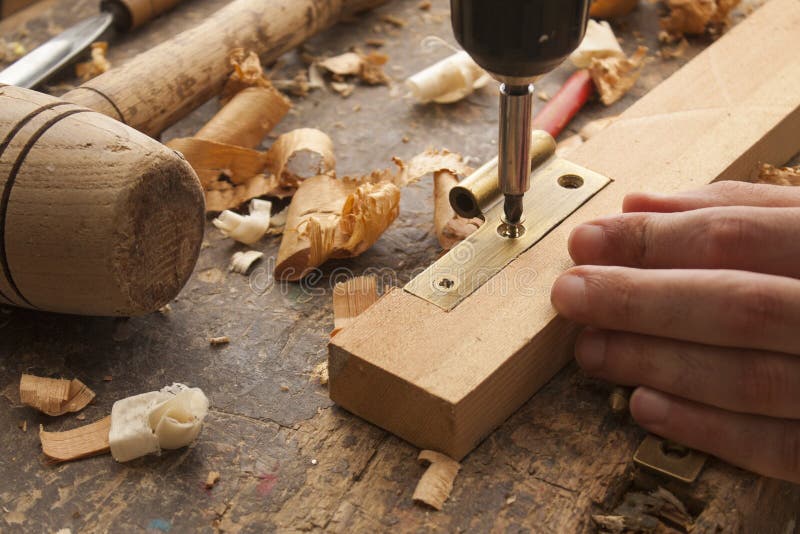 Close up of a carpenter screwed a hinge on a wooden plank