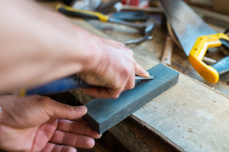 Carpenter sharpening a chisel in a small workshop royalty free stock photo