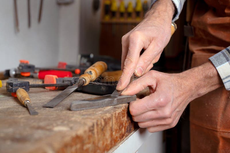 Carpenter sharpening a chisel. woodworking process with hand tools in a carpentry workshop. wood carving concept stock photo