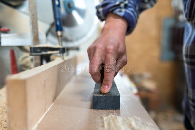 Carpenter sharpens a chisel in a small workshop stock photos