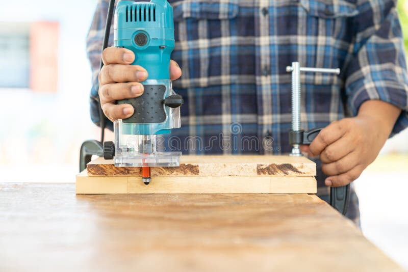 The Carpenter Using a Electric Trimmer To Cut Edging Wooden Board Stock