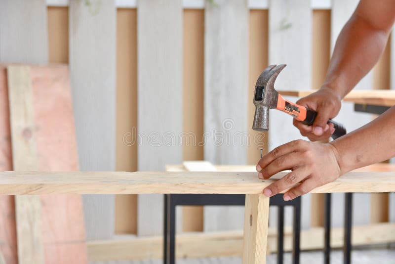 Carpenter using the hammer hit a nail