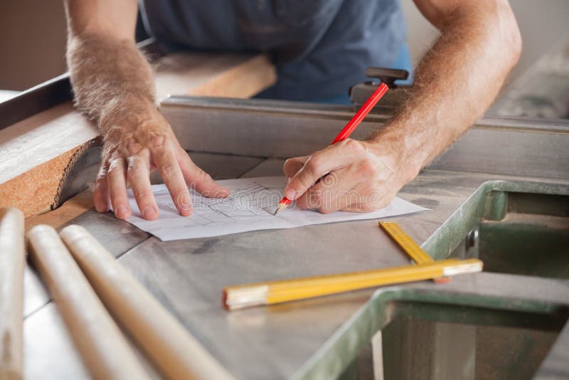 Carpenter Working On Blueprint At Tablesaw stock photography
