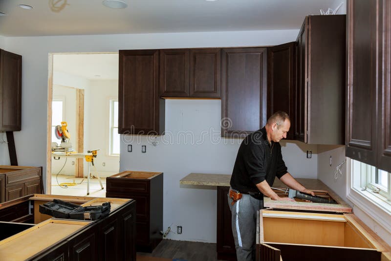 Carpentiere che installa i gabinetti e ripiano in una cucina e parzialmente installato