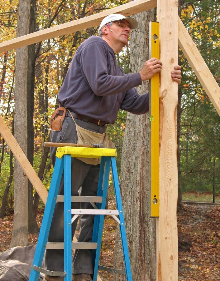 Carpenter checking level of wood framing. Carpenter checking level of wood framing