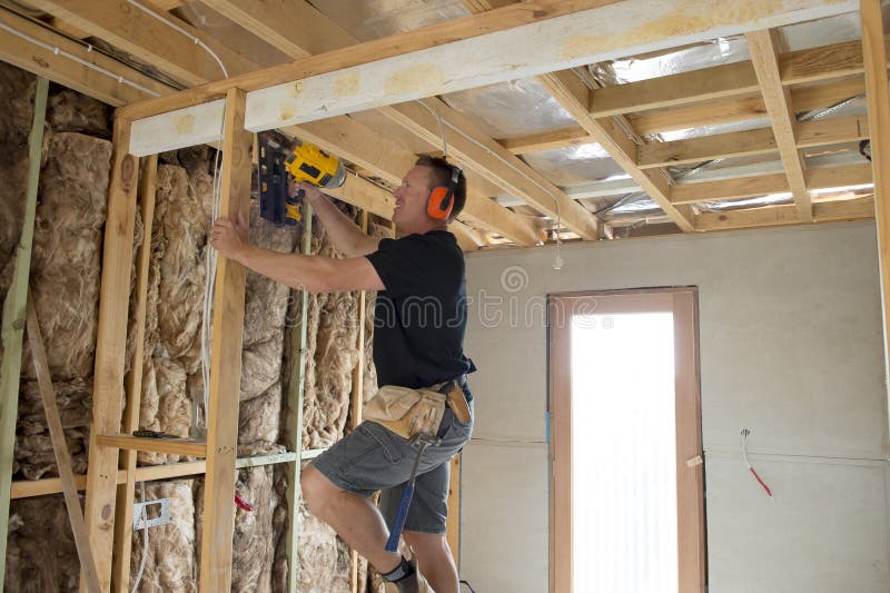 Carpintero atractivo y confiado del constructor o madera de trabajo del hombre del constructor con el taladro eléctrico en el emp imagenes de archivo