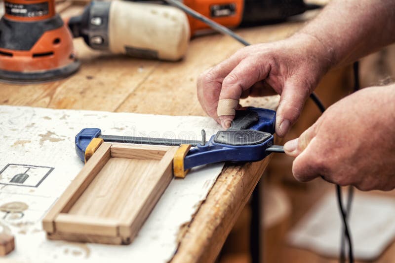 Carpintero mayor del primer que pega la superficie de madera del arte y que se une a con las abrazaderas Carpintero de la artesan foto de archivo Carpintero mayor del primer que pega la superficie de madera del arte y que se une a con las abrazaderas Carpintero de la artesan foto de archivo
