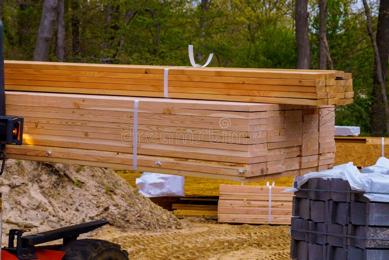 Carrello elevatore che muove una pila di 2 x 4 perni del legname ad una piccola elaborazione di ceppo fotografie stock libere da diritti Carrello elevatore che muove una pila di 2 x 4 perni del legname ad una piccola elaborazione di ceppo fotografie stock libere da diritti