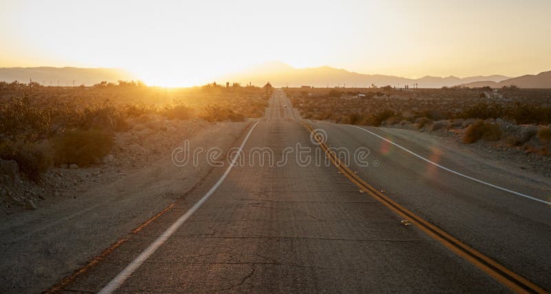 Carretera nacional a través del desierto que mira hacia el sol poniente en horizonte imágenes de archivo libres de regalías Carretera nacional a través del desierto que mira hacia el sol poniente en horizonte imágenes de archivo libres de regalías