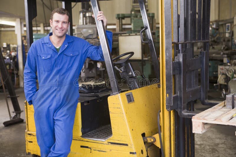 Warehouse worker standing by a yellow forklift. Warehouse worker standing by a yellow forklift.