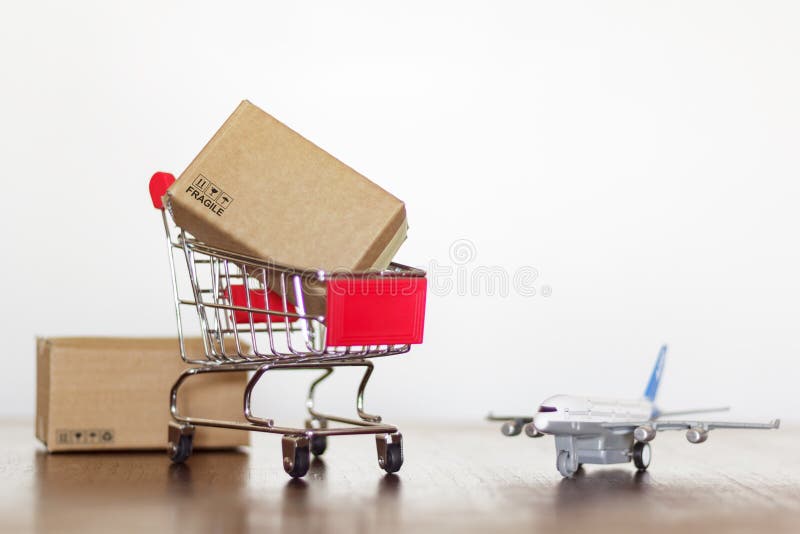 Trolley with cartons and airplane on wooden table. Worldwide Shopping and shipping concept. Trolley with cartons and airplane on wooden table. Worldwide Shopping and shipping concept