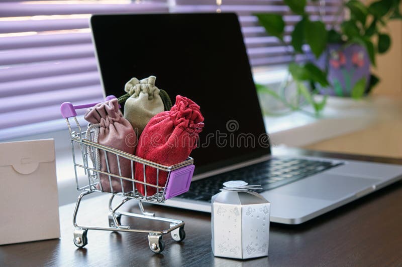 Carrito de compras de juguetes para un supermercado con regalos y compras en una mesa con un portátil en el fondo. imagen conceptual de tiendas en línea
