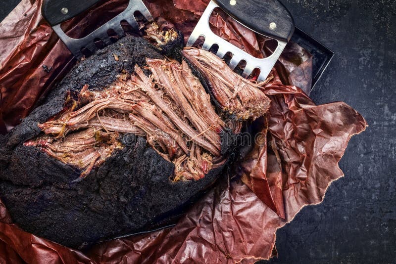 Carro barbecue tradizionale estratto con carne di manzo in carta da pesca con artigli di carne su un pannello rustico