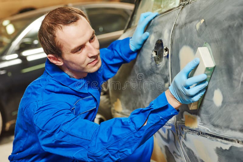 Auto mechanic worker sanding polishing bumper car at automobile repair and renew service station shop by sandpaper. Auto mechanic worker sanding polishing bumper car at automobile repair and renew service station shop by sandpaper