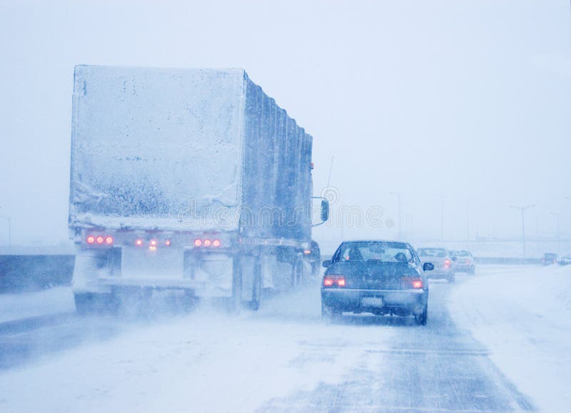 A snow covered transport truck and a passenger car driving in almost whiteout conditions in Canada. A snow covered transport truck and a passenger car driving in almost whiteout conditions in Canada.