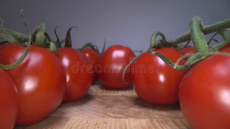 Carro tirado de tomates alegres rojos encima de fondo de madera de la tabla Deslizándose a través de verduras de cosecha propia