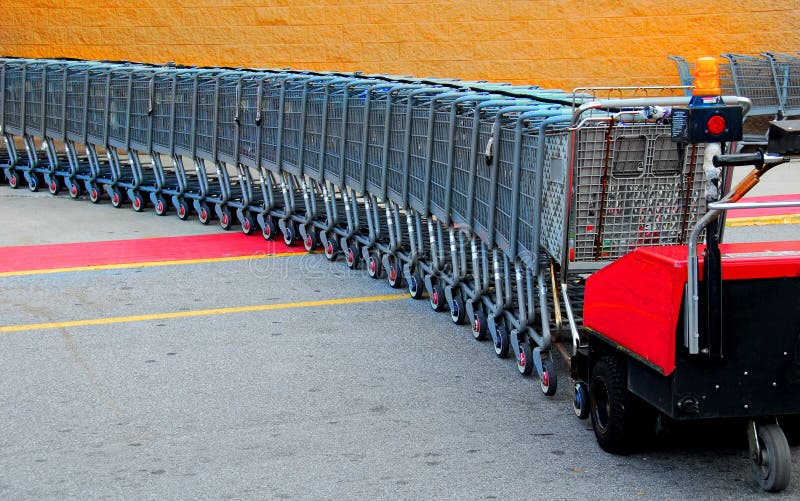 Shopping carts being collected by moving cart pusher. Shopping carts being collected by moving cart pusher
