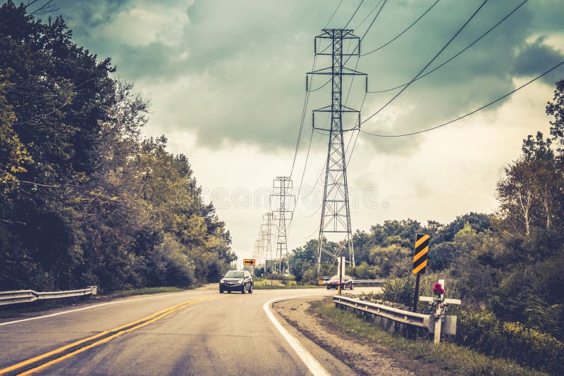 Carros que viajam em uma estrada em torno de um canto com uma cruz no primeiro plano um lembrete desagradável para conduzir com s fotografia de stock royalty free Carros que viajam em uma estrada em torno de um canto com uma cruz no primeiro plano um lembrete desagradável para conduzir com s fotografia de stock royalty free