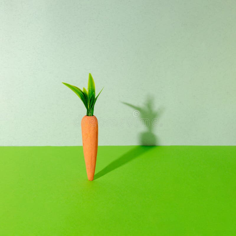 Carrot with creative shadow on gray and green background. Minimal Easter concept. Spring minimal composition stock photography