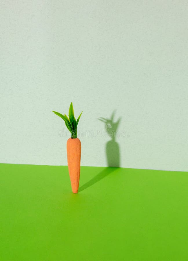 Carrot with creative shadow on gray and green background. Minimal Easter concept. Spring minimal composition royalty free stock images