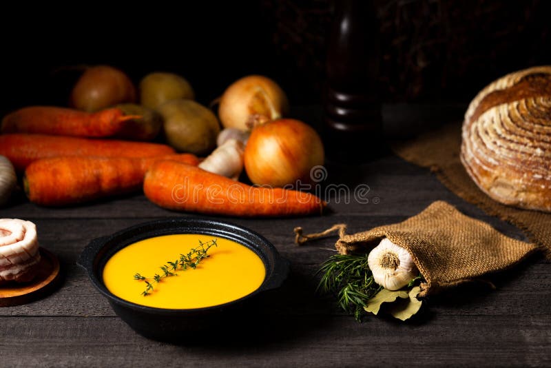 Carrot and potato soup with thyme twig on a grey wood table with onion, potatoes, carrot, garlic, bread loaf, pork belly, laurel royalty free stock images Carrot and potato soup with thyme twig on a grey wood table with onion, potatoes, carrot, garlic, bread loaf, pork belly, laurel royalty free stock images