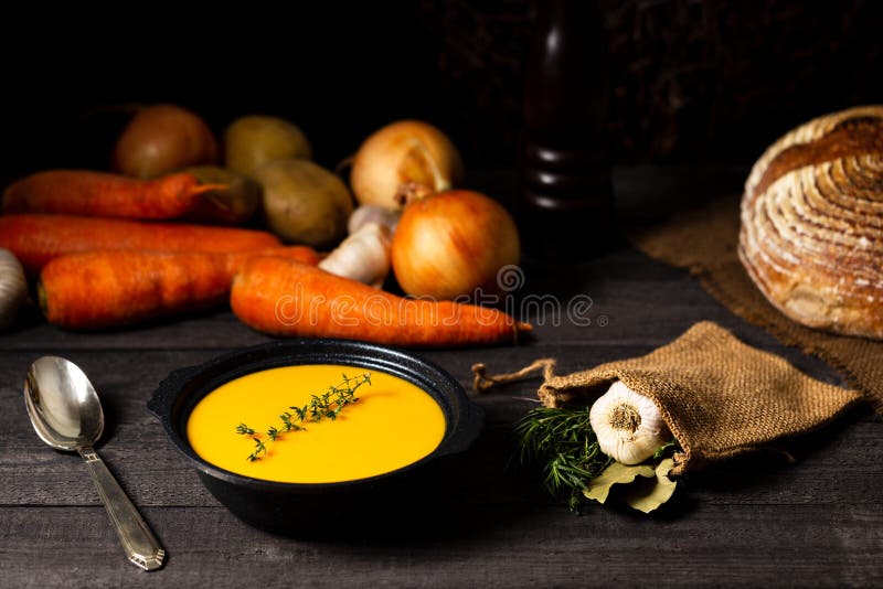 Carrot and potato soup with thyme twig on a grey wood table with onion, potatoes, carrot, garlic, bread loaf, vintage silver spoon royalty free stock image Carrot and potato soup with thyme twig on a grey wood table with onion, potatoes, carrot, garlic, bread loaf, vintage silver spoon royalty free stock image