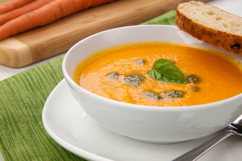 Cremosa zuppa di carote con olio al basilico, guarnito con erba di grano intero pane.