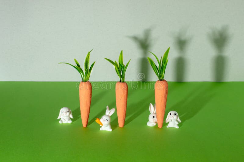 Carrots with little white bunnies on gray and green background. Minimal Easter concept. Spring minimal composition stock photo