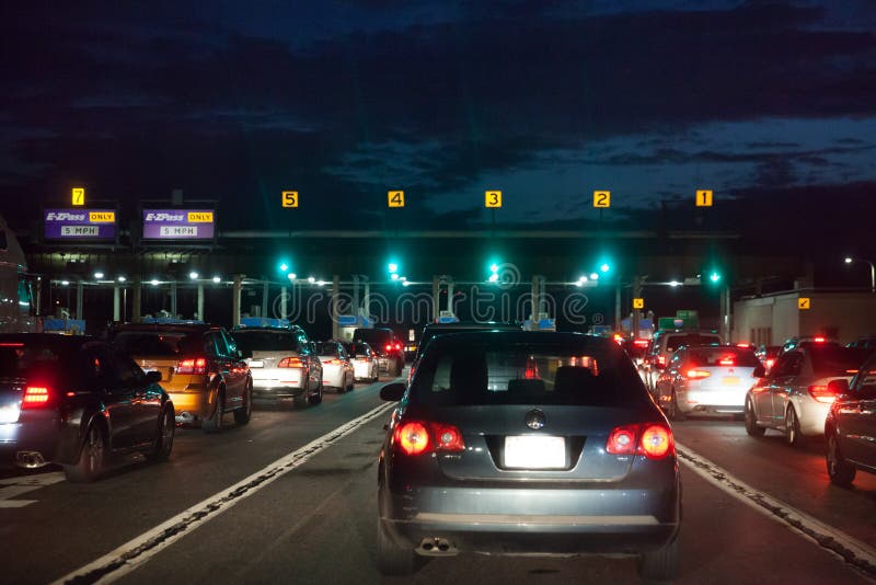 Cars in a line up at night to pay for toll fee so that they can use or leave the road funded by private companies. This is one of the toll gate in United States of America. Cars in a line up at night to pay for toll fee so that they can use or leave the road funded by private companies. This is one of the toll gate in United States of America.