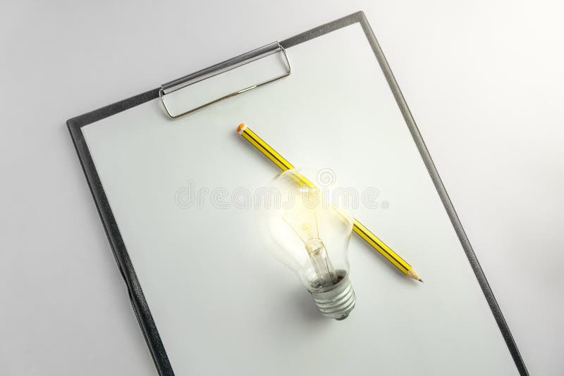 Carta in bianco con una lampadina e concetto aspettante di idea della matita con luce fotografia stock Carta in bianco con una lampadina e concetto aspettante di idea della matita con luce fotografia stock