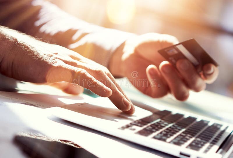 Carta di credito della mano della tenuta dell'uomo del primo piano Compera di pagamenti di Use Laptop Online dell'uomo d'affari G immagine stock