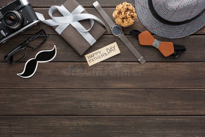 Happy Fathers Day card on rustic wood background with border of present, watch, hat and other man things. Happy Fathers Day card on rustic wood background with border of present, watch, hat and other man things