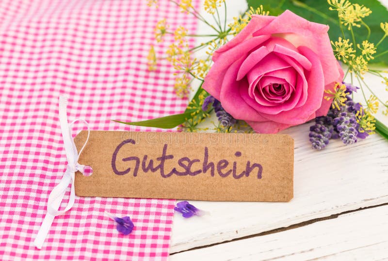 Carte cadeaux avec le mot allemand, le Gutschein, le bon de moyens ou le bon et le beau bouquet de fleurs photos stock Carte cadeaux avec le mot allemand, le Gutschein, le bon de moyens ou le bon et le beau bouquet de fleurs photos stock