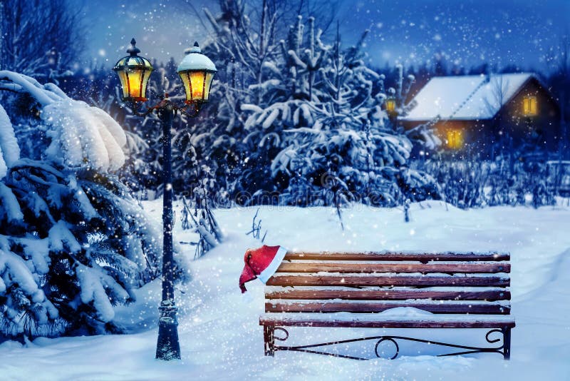 Carte d'art de Noël Chapeau de Père Noël sur un banc dans la neige sur fond de la forêt de Noël Maison Village dans la b
