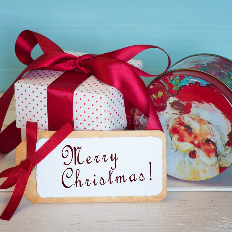 Carte de Joyeux Noël avec un vintage Santa Candy Tin et présent rouge et blanc de cadeau attaché avec un arc rouge de satin et un images libres de droits Carte de Joyeux Noël avec un vintage Santa Candy Tin et présent rouge et blanc de cadeau attaché avec un arc rouge de satin et un images libres de droits