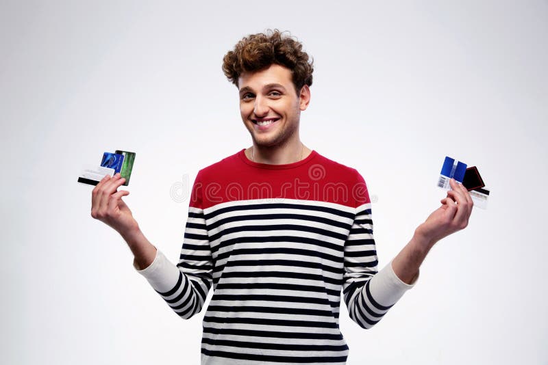 Carte di credito casuali felici della tenuta dell'uomo fotografia stock Carte di credito casuali felici della tenuta dell'uomo fotografia stock