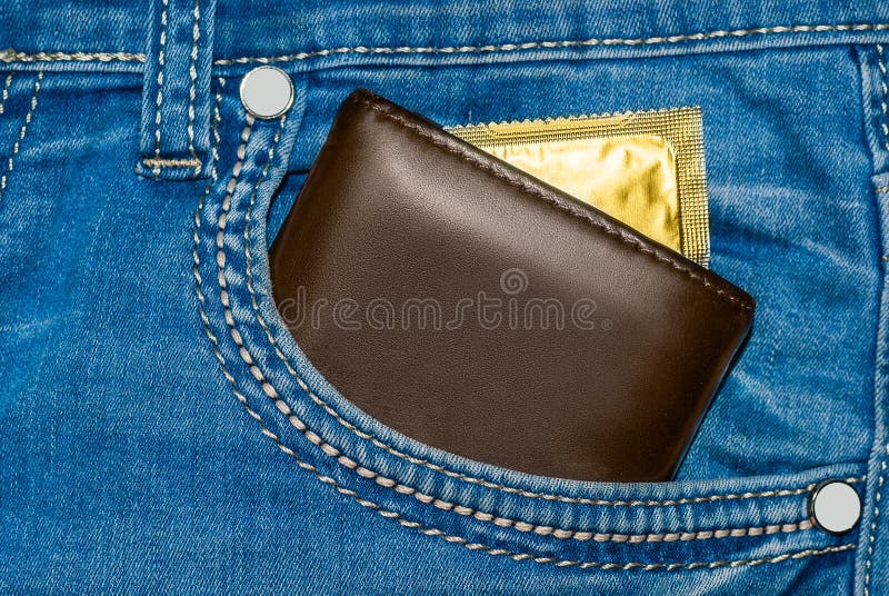 Carteira em um bolso da calças de ganga com um preservativo do ouro imagem de stock Carteira em um bolso da calças de ganga com um preservativo do ouro imagem de stock