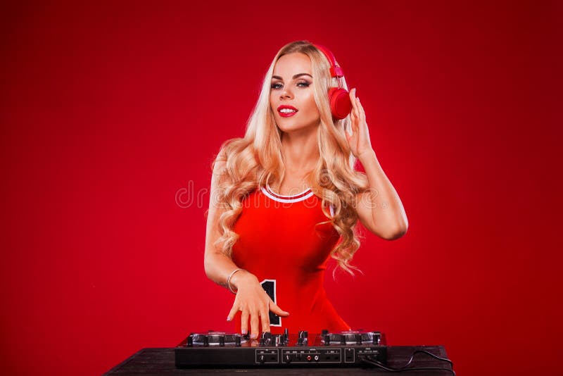 Cartel para el partido de DJ Retrato de la mujer atractiva con la cubierta que juega música en fondo rojo de la Navidad fotografía de archivo libre de regalías Cartel para el partido de DJ Retrato de la mujer atractiva con la cubierta que juega música en fondo rojo de la Navidad fotografía de archivo libre de regalías