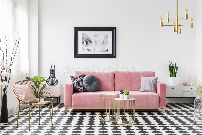 Cartel sobre el sofá rosado en interior de la sala de estar con la butaca del oro en piso a cuadros Foto verdadera